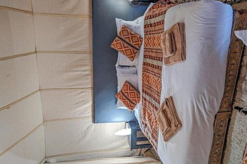 A bed with patterned pillows and a blanket, a bedside table, and a wall with a geometric pattern. 3