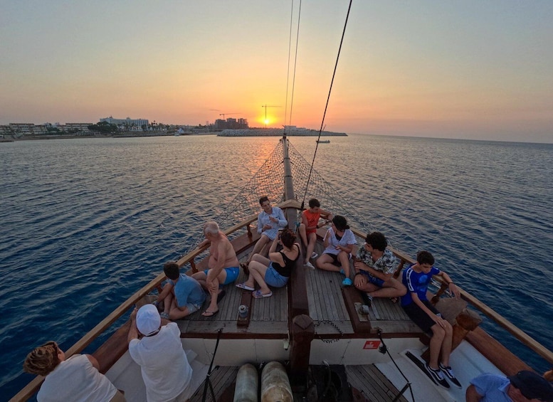 A group of people on a boat at sunset with a city skyline in the background. 2