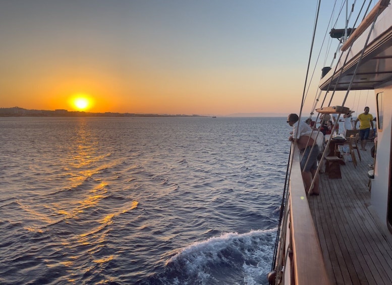 A sunset over the ocean with a boat deck and people on board. 4