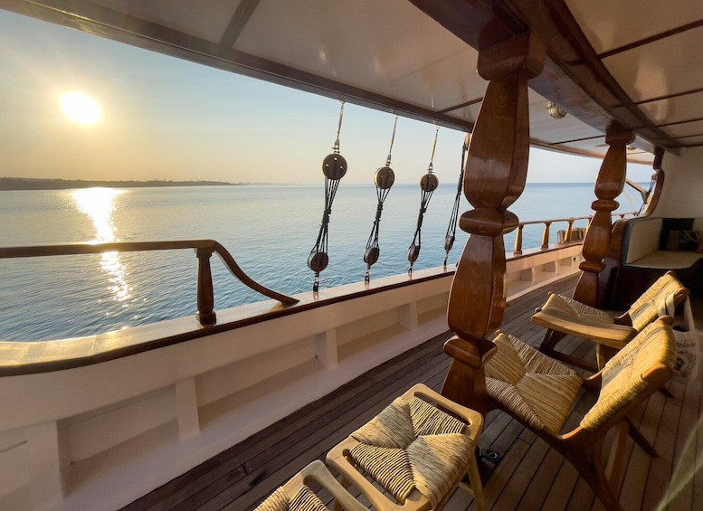 A deck with wicker chairs, a wooden balustrade, and a view of the sea at sunset. 3
