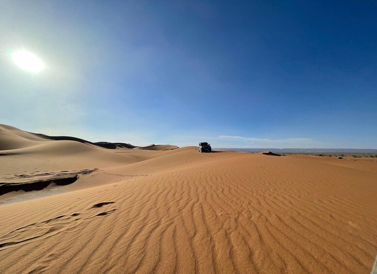 A desert landscape with sand dunes and a vehicle in the distance. 2