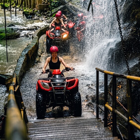 People riding ATVs down a water slide in a park. 1