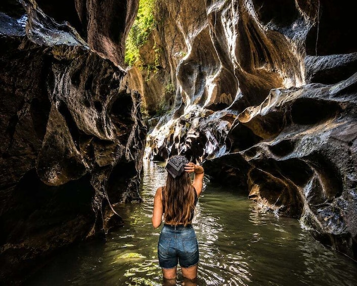 A person standing in a cave with water flowing over rocks. 2
