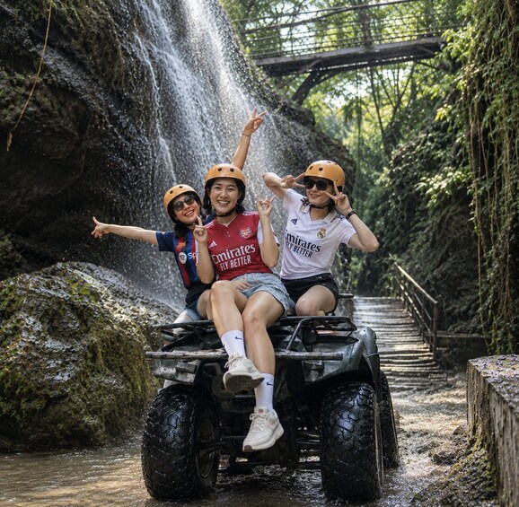 Three people on an ATV near a waterfall. 2