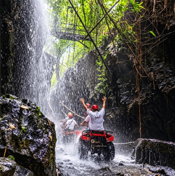 A group of people on an ATV navigating a rocky stream with water cascading over rocks. 5