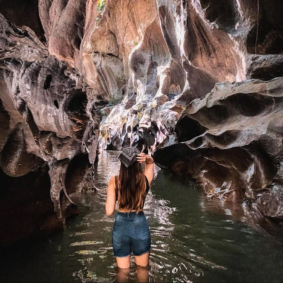 A person standing in a cave with water flowing from the ceiling. 2
