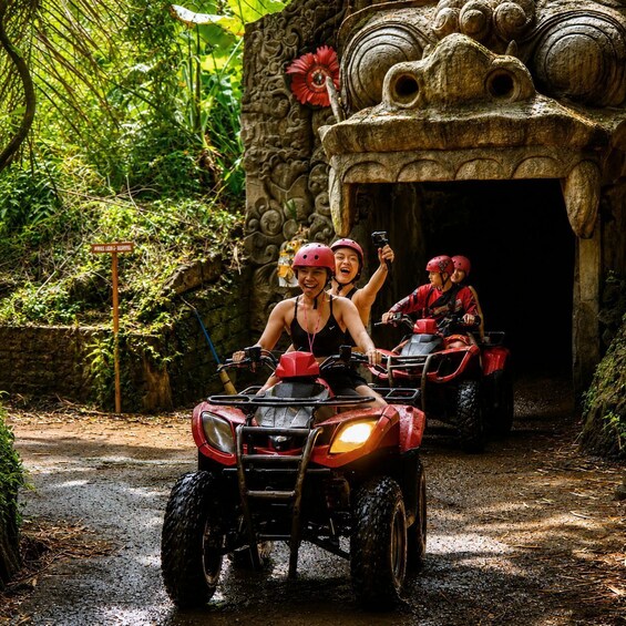 Two people on an ATV in a jungle setting with a stone structure in the background. 3