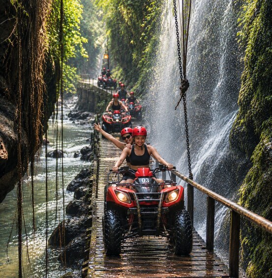 A person riding an ATV on a wet bridge with a waterfall in the background. 1