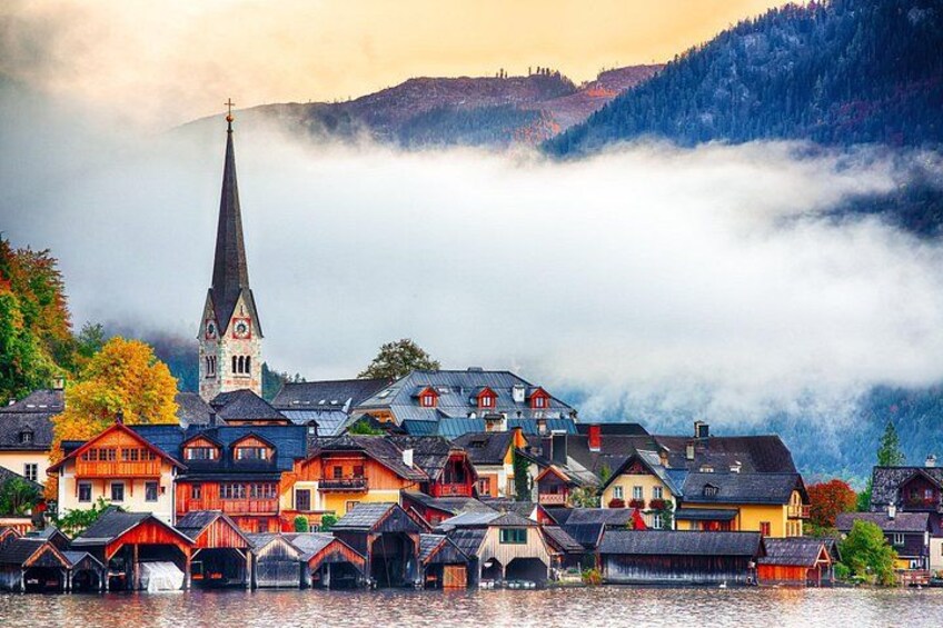 Un pueblo junto al lago con casas tradicionales, una aguja de iglesia y montañas al fondo. 2