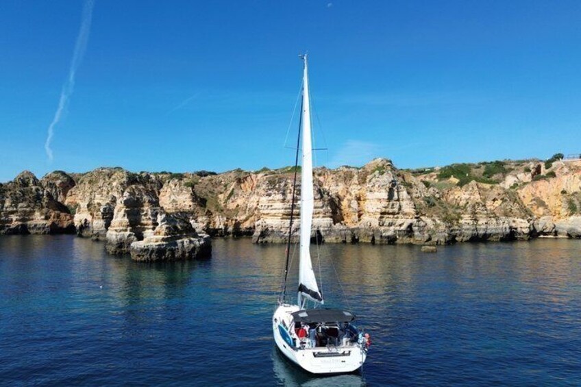 A sailboat on calm waters with rocky cliffs in the background. 3