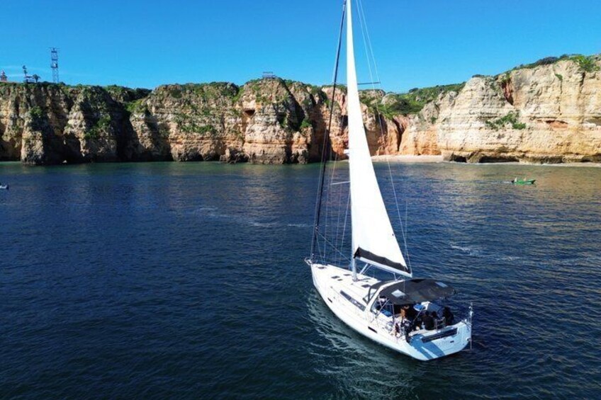 A sailboat on calm waters with cliffs in the background. 1