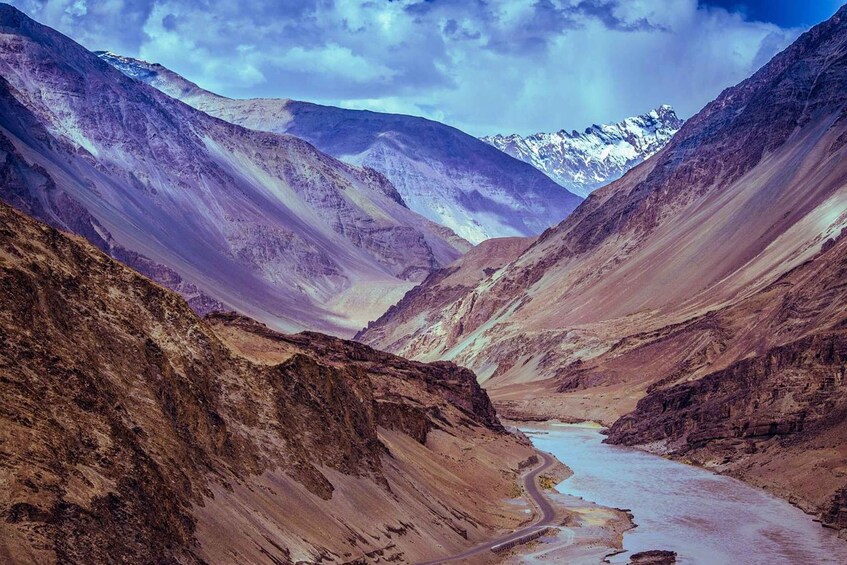 A mountain valley with a river, snow-capped peaks, and a winding road. 1