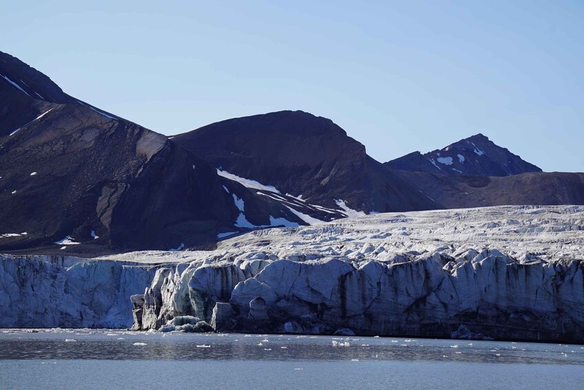 A glacier with ice cliffs and a body of water in the foreground. 3