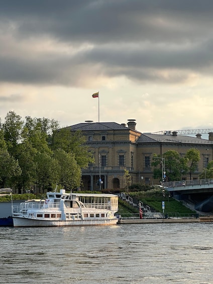 A river with a boat, a building with a flag, and a bridge. 1