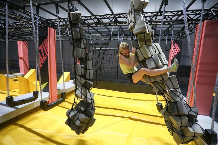 A person performing an acrobatic maneuver on a trapeze-like apparatus in an indoor gym. 1