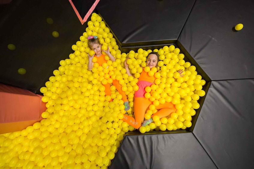 Two children playing in a ball pit filled with yellow balls. 5