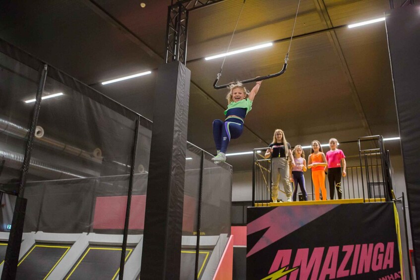 A trampoline park with a person performing on a trapeze. 4
