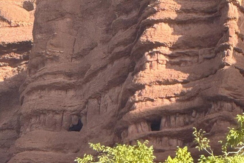 A large rock formation with layered sedimentary structures and small caves. 3