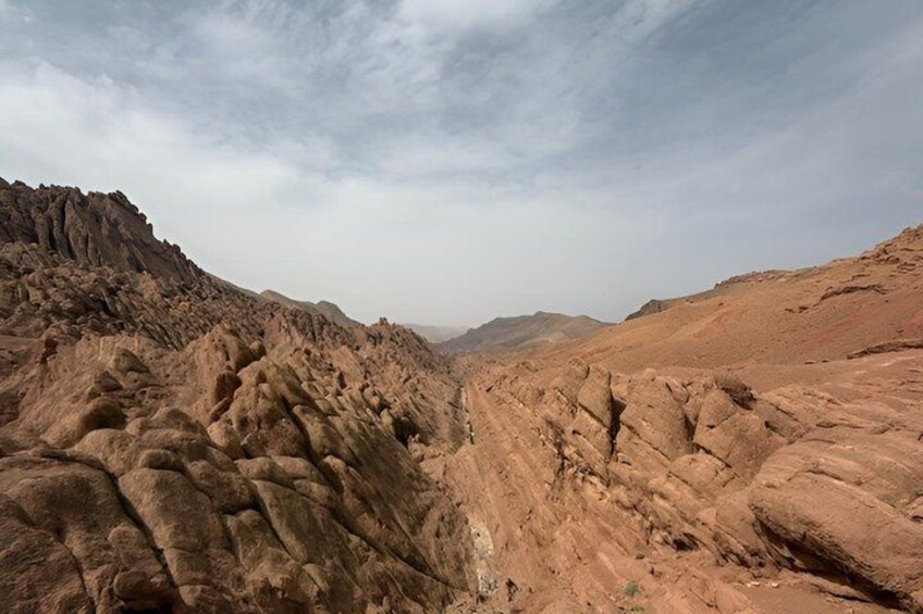 A rugged desert landscape with eroded rock formations and a clear sky. 1