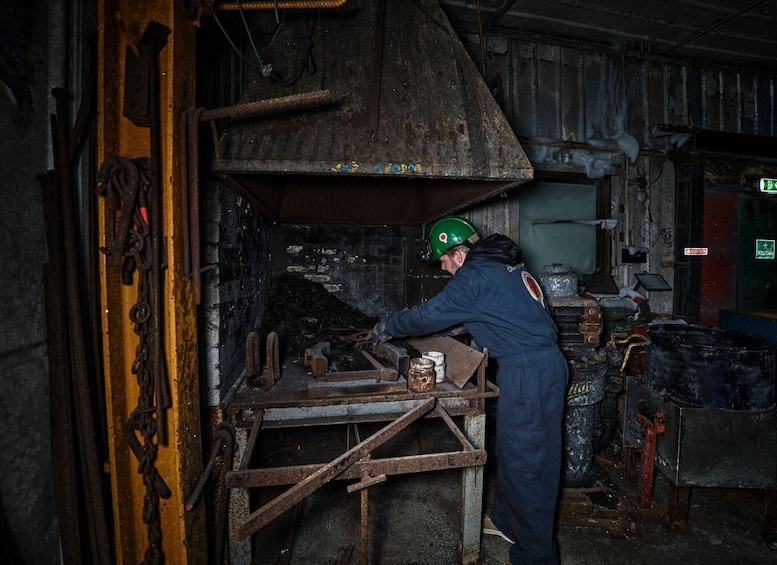 A person working with machinery in a dimly lit industrial setting. 4
