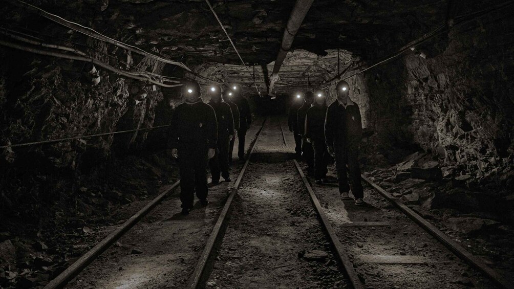 A dimly lit tunnel with tracks and overhead cables. 1