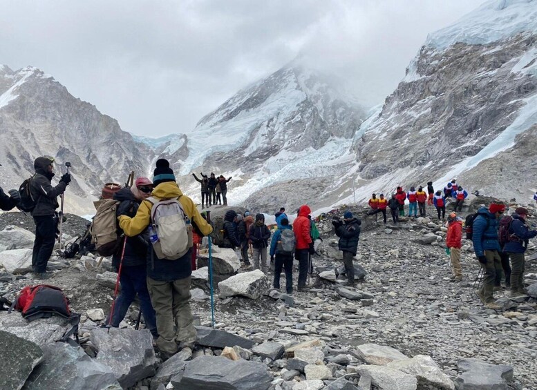 A group of hikers on a rocky mountain trail with snow-capped peaks in the background. 5
