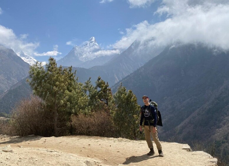A hiker on a mountain trail with snow-capped peaks in the background. 3