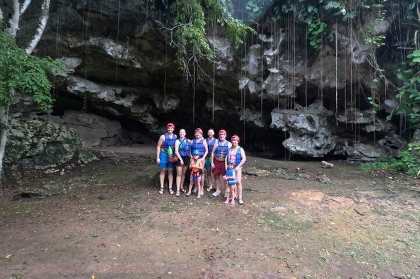 A group of people standing in front of a rocky cave entrance. 3