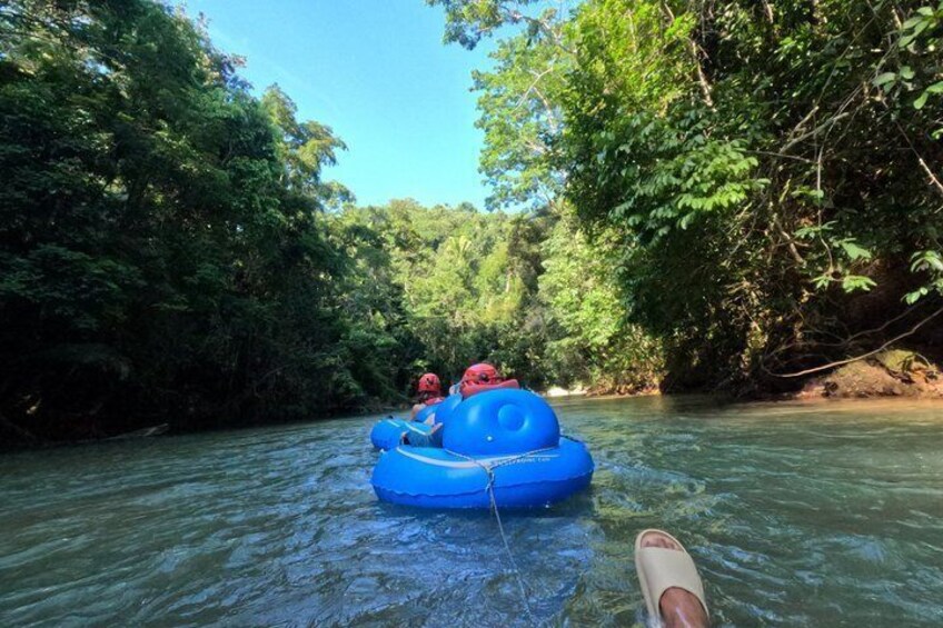 A person in a blue raft on a river surrounded by dense greenery. 5