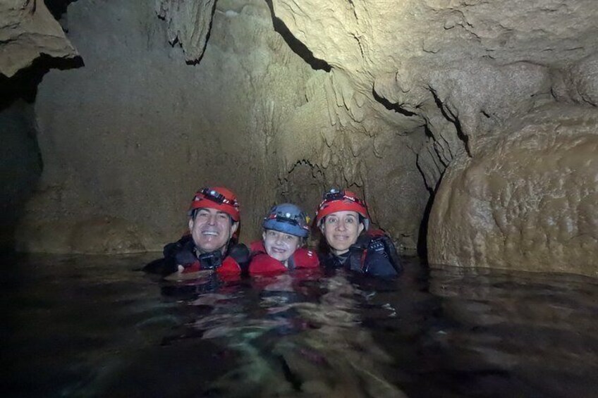 Tres personas en una cueva con agua, usando cascos y chalecos salvavidas. 3