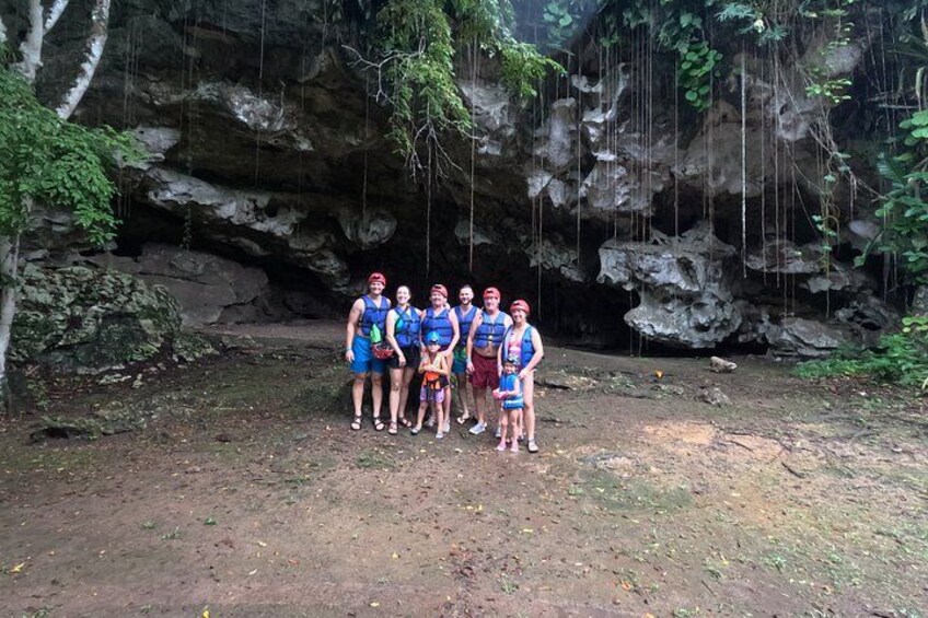 Un grupo de personas de pie frente a la entrada de una cueva rocosa. 2