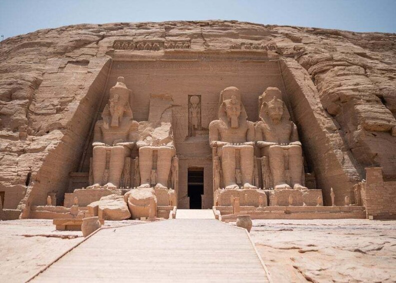 A large ancient Egyptian temple with seated statues of pharaohs at the entrance. 5