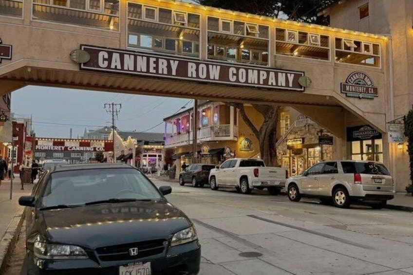 Une rue avec une enseigne indiquant « Cannery Row Company », des voitures garées et des bâtiments en arrière-plan. 4