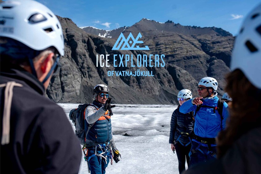 A group of ice climbers in a mountainous area with a glacier in the background. 1