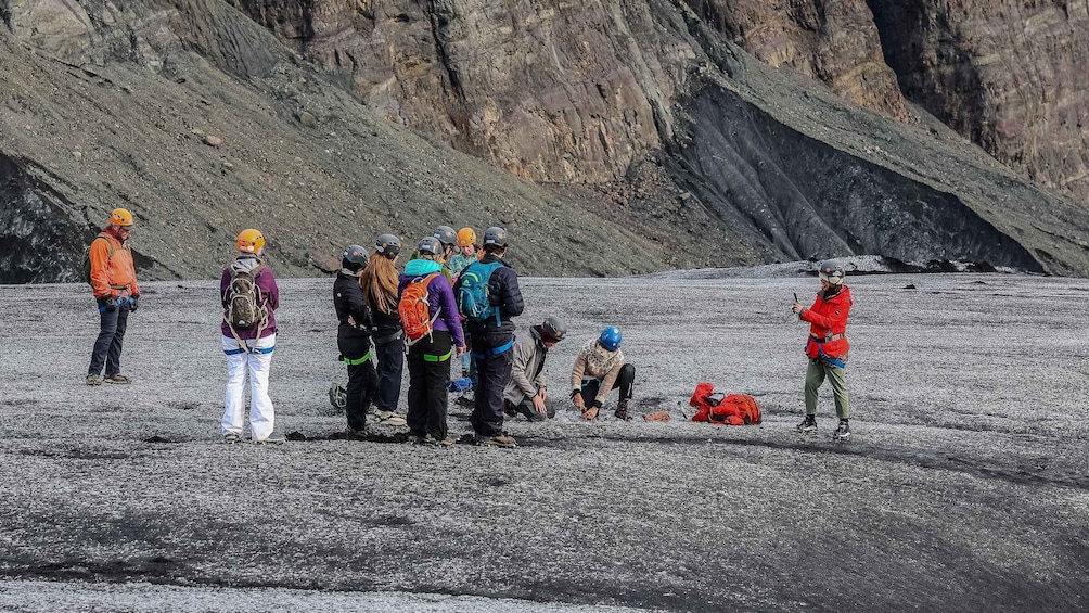A group of people on a rocky terrain with mountains in the background. 2