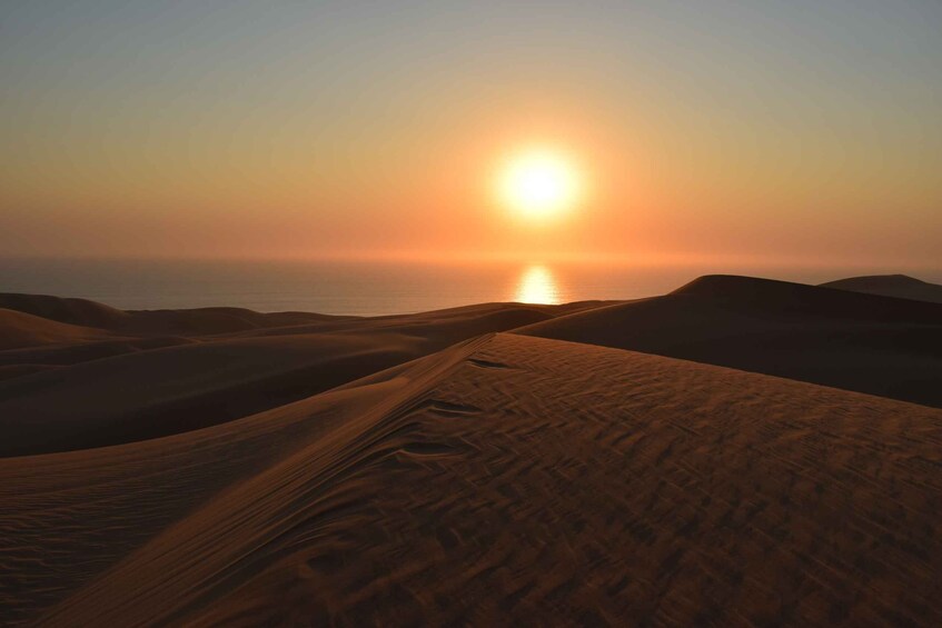 A desert landscape with sand dunes and a setting sun. 2