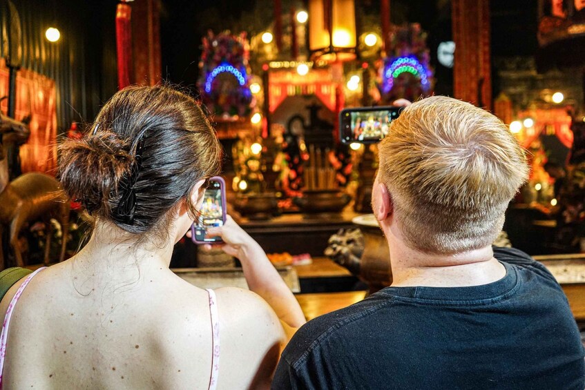 Two people taking a photo of a temple with colorful lights. 3