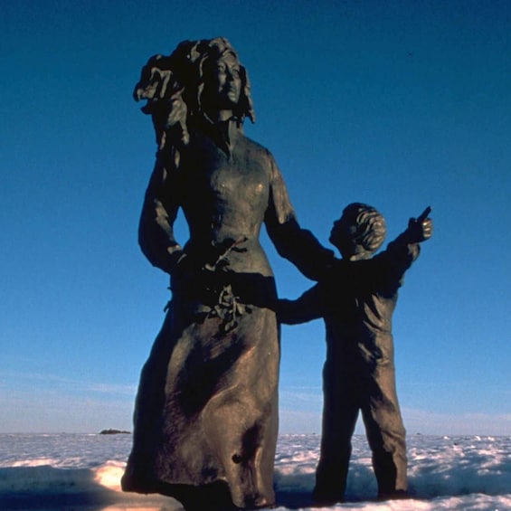 A statue of a woman and a child on a beach. 3