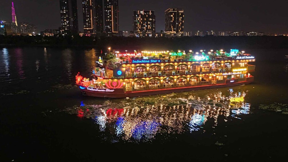 A brightly lit riverboat with multiple decks and neon signs, floating on a river with a city skyline in the background. 5