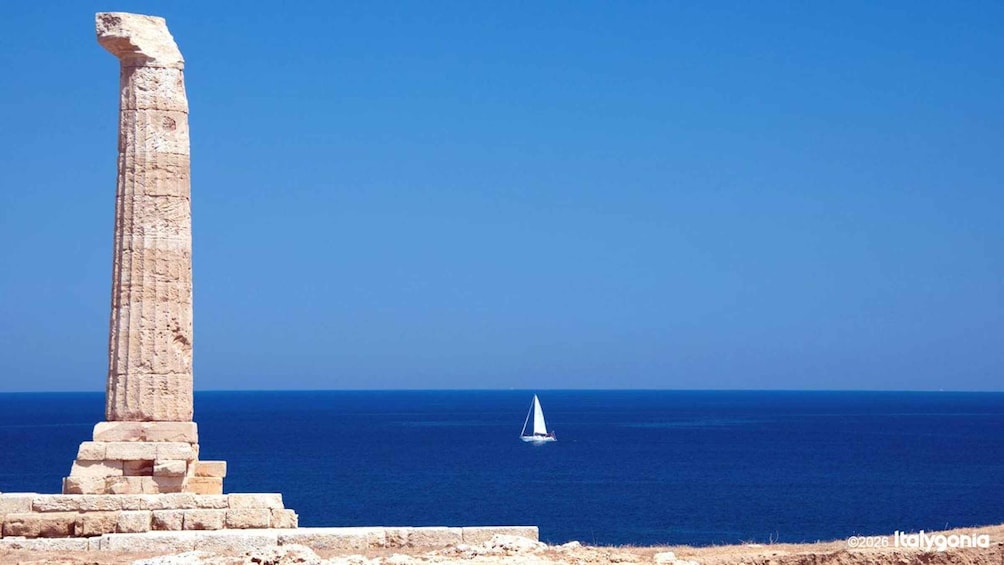 A stone column and a sailboat on the sea. 1
