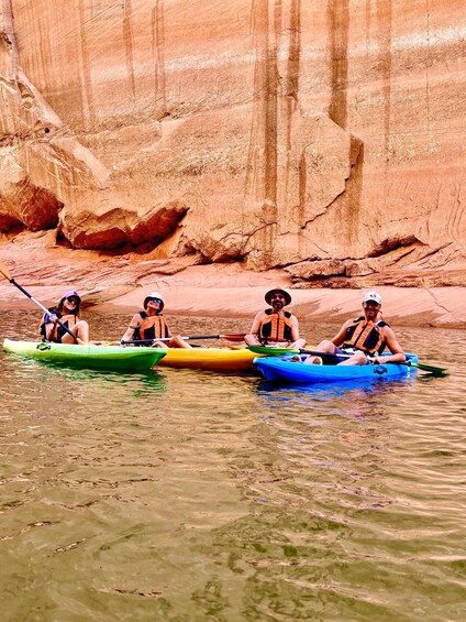 Four people kayaking on a river with a rocky canyon in the background. 5