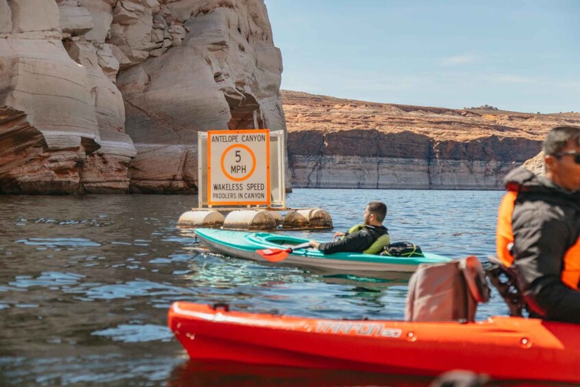 A canyon with a speed limit sign, a paddle boat, and a red kayak. 3