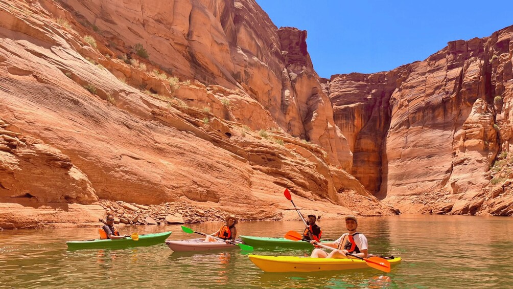 People kayaking on a river surrounded by red rock cliffs. 1