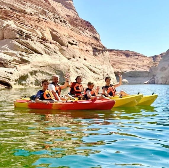 People kayaking on a calm river with rocky cliffs in the background. 3