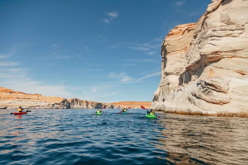 Kayakers on a calm sea with white rock formations in the background. 4