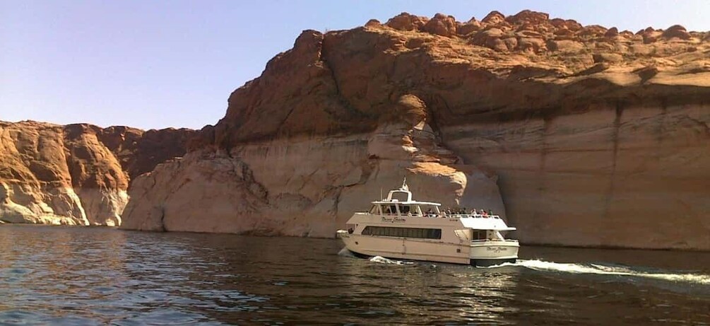 A boat on water with a large rock formation in the background. 1