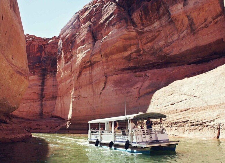 A boat navigating through a narrow canyon with red rock walls. 3