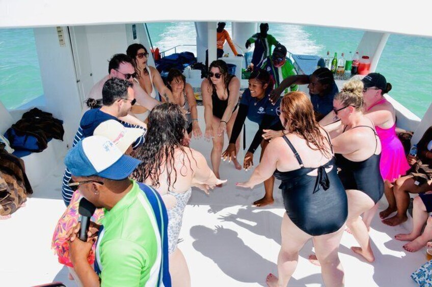 Un grupo de personas en un barco, algunas de pie y otras sentadas, con el océano al fondo. 5