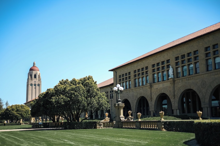 A building with a clock tower, arched windows, and a well-maintained lawn. 4