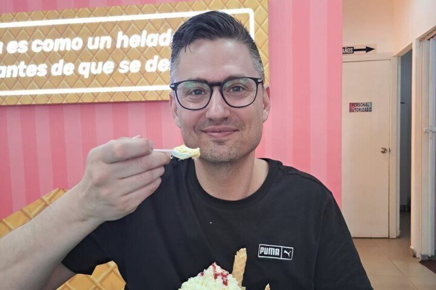 A person in a black Puma t-shirt eating ice cream with a waffle cone. 4
